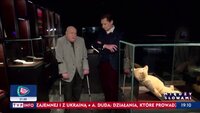 Zenon Puchalski w sali muzeum  stoi o kulach obok dziennikarza