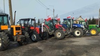 Ciągniki rolnicze z flagami polski ustawione w rzędzie blokują drogę
